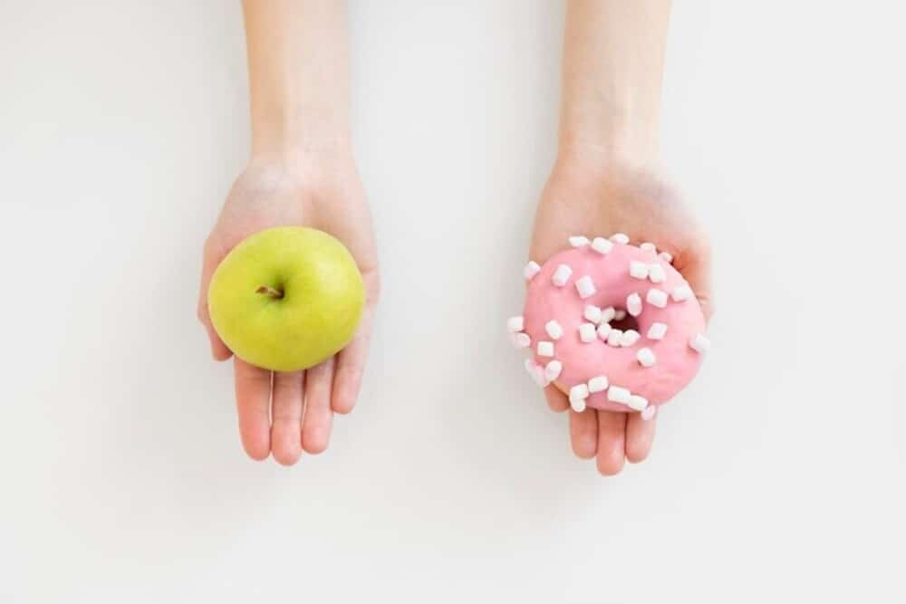 manos sosteniendo manzana y donut