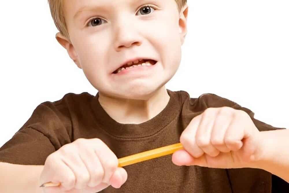 niño con impulsividad intentando romper lápiz